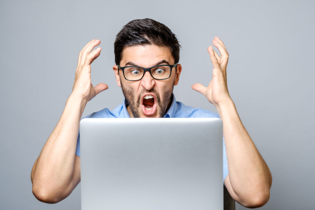 Home portrait of amazed man with laptop computer over gray background